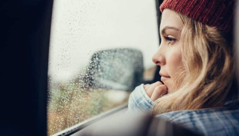Frau schaut aus dem Fenster und fragt sich "Bindungsangst oder Narzissmus?"